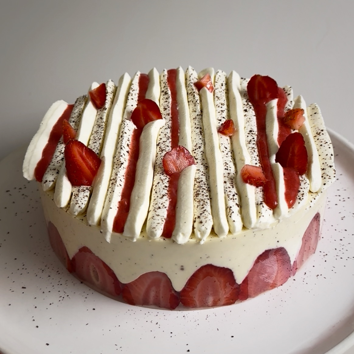 Strawberry Fraisier Cake with straight lines piped on top, strawberry confit and fresh strawberries.