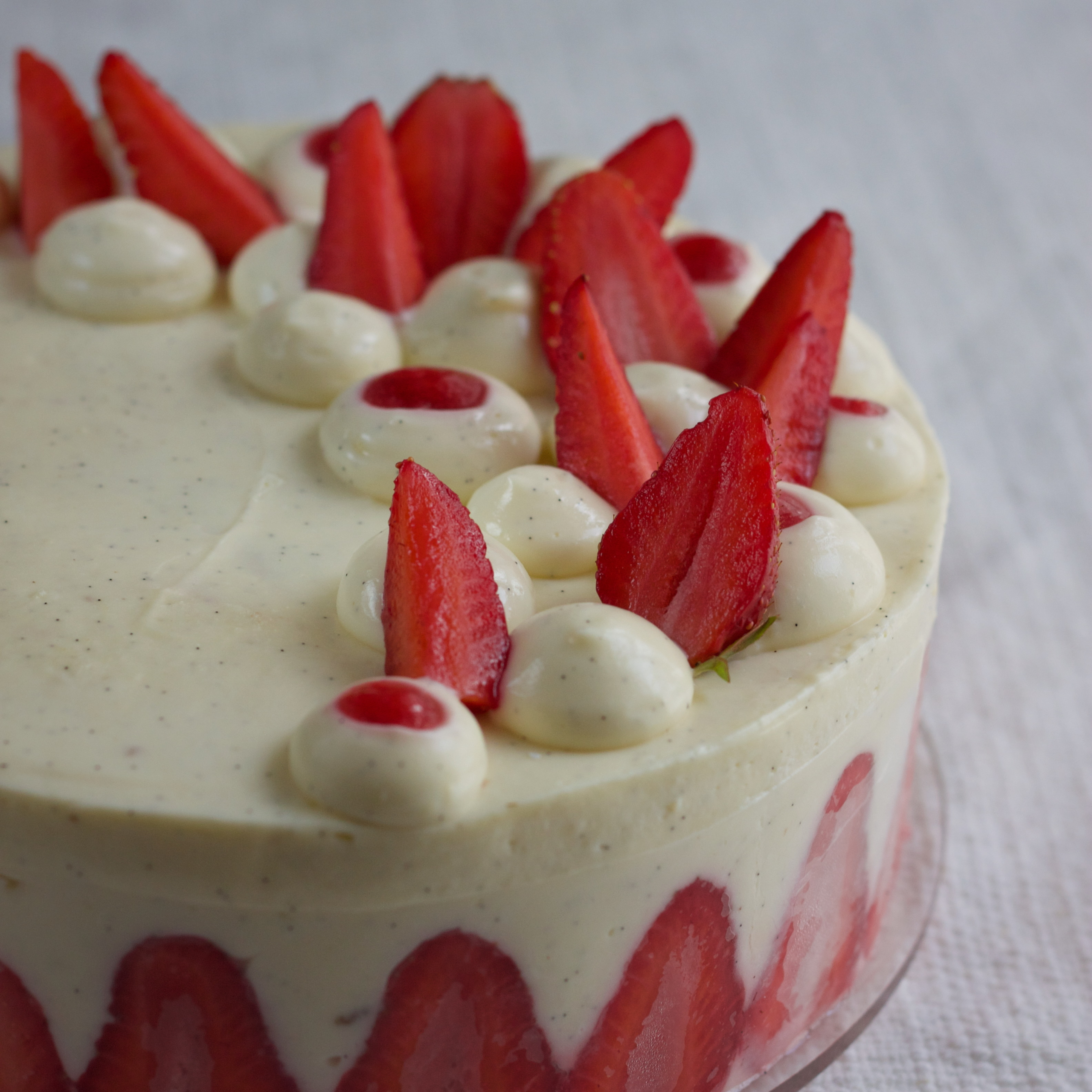 Strawberry Fraisier Cake with dollops piped on top, some filled with strawberry confit and fresh strawberries.