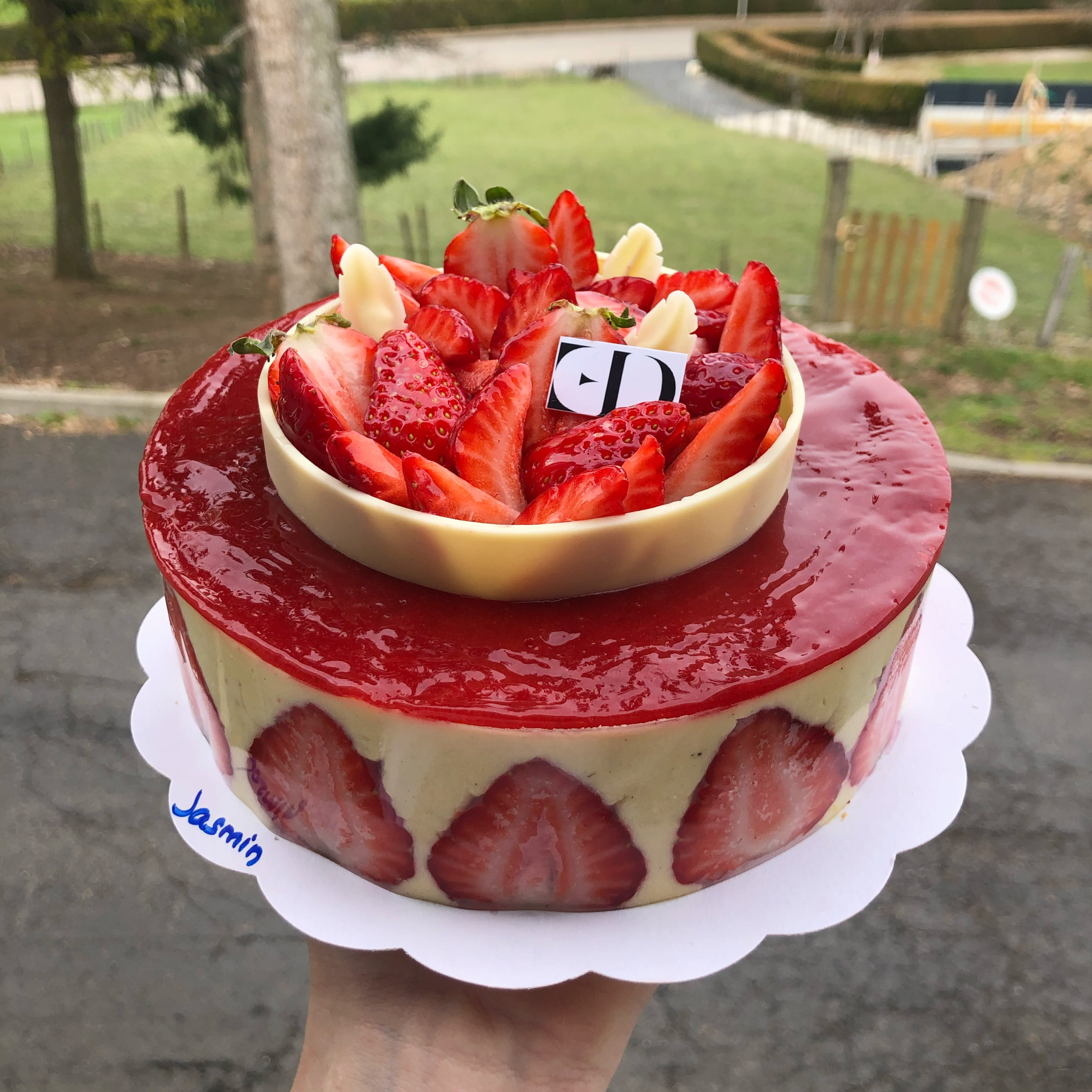 Strawberry Fraisier Cake with a strawberry confit disc on top, a white chocolate ring on top, filled with fresh strawberries.